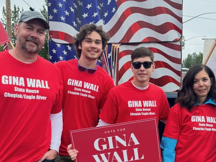 The Wall family in red Gina Wall shirts at the parade, holding a Vote for Gina Wall sign