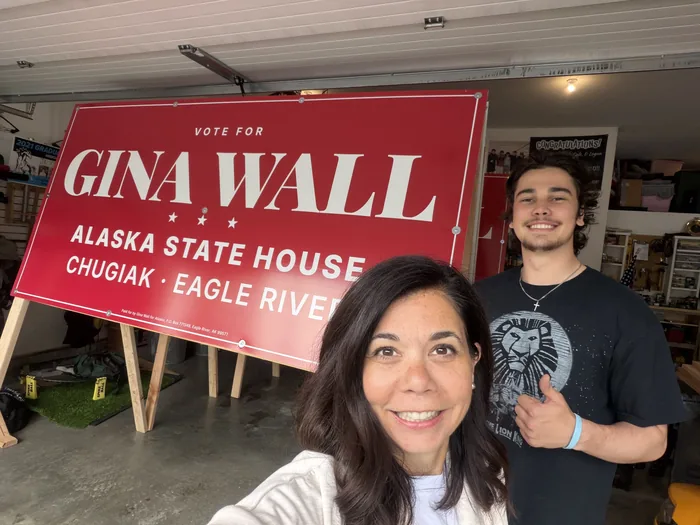 Gina Wall and her son with a Vote for Gina Wall yard sign