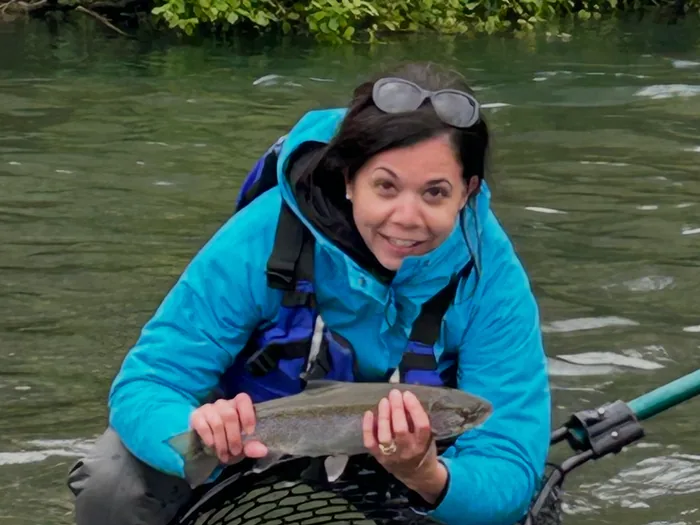 Gina Wall holding a rainbow trout over a landing net
